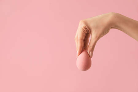 Hand with makeup sponge on color backgroundの写真素材