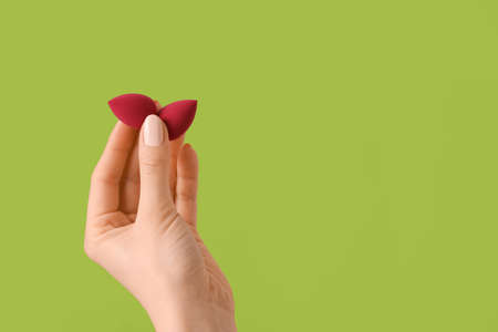Hand with makeup sponges on color backgroundの写真素材