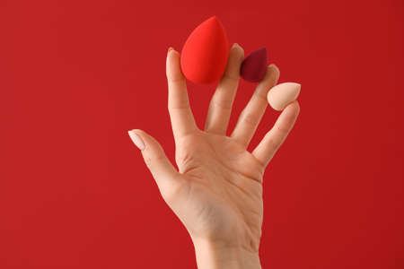 Hand with makeup sponges on color backgroundの写真素材