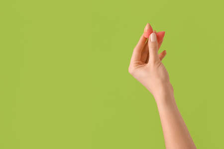 Hand with makeup sponges on color backgroundの写真素材