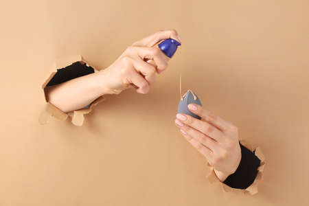 Hands with makeup sponge and concealer visible through holes in color paper