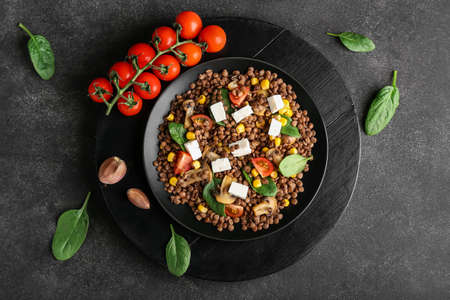 Plate with tasty cooked lentils, vegetables and cheese on dark backgroundの写真素材