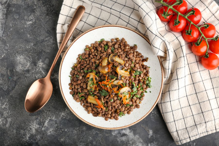 Plate with tasty cooked lentils and mushrooms on grunge backgroundの写真素材