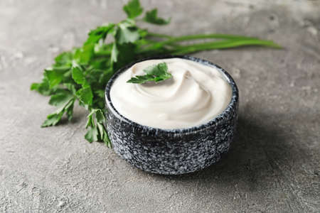 Bowl of tasty sour cream and herbs on grunge backgroundの写真素材
