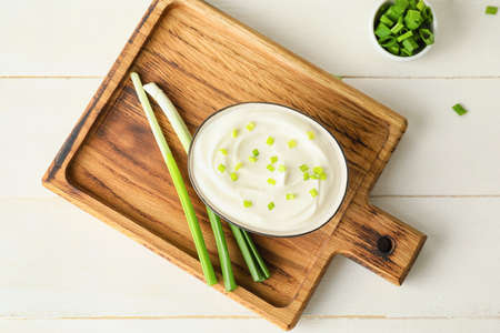 Bowl of tasty sour cream and green onion on white wooden backgroundの写真素材