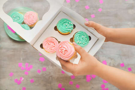 Woman holding box with tasty cupcakes on gray backgroundの写真素材