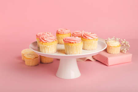 Dessert stand with tasty cupcakes on color backgroundの写真素材