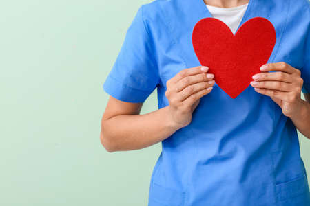 Cardiologist with red heart on color background