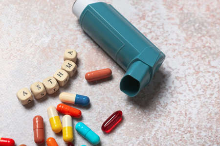 Modern inhaler, pills and word ASTHMA on grunge background, closeupの写真素材