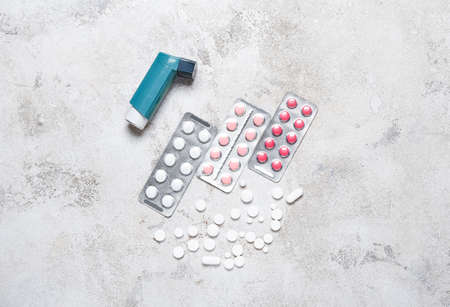 Modern inhaler and pills on grunge background