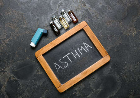 Modern inhaler, ampules and chalkboard with word ASTHMA on dark backgroundの写真素材