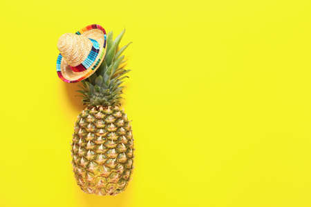 Fresh pineapple in sombrero on color backgroundの写真素材