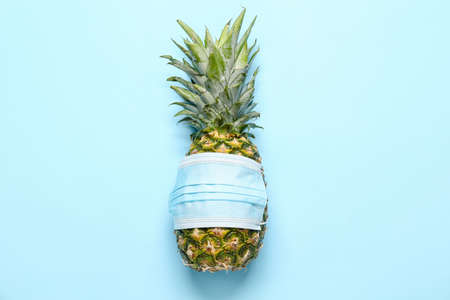 Fresh pineapple in medical mask on color backgroundの写真素材