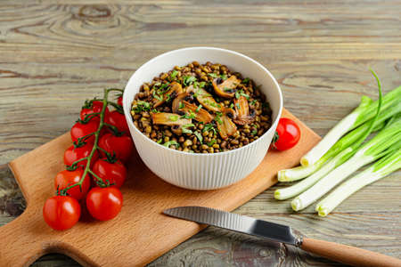 Bowl of tasty cooked lentils and mushrooms on tableの写真素材