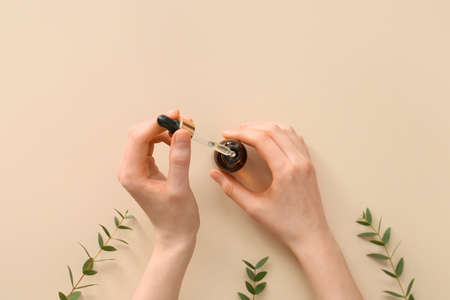 Female hands with bottle of essential oil on color backgroundの写真素材