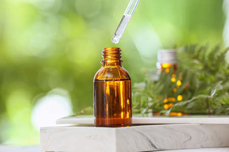 Bottle of essential oil on table outdoors, closeup