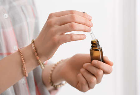 Woman holding bottle of essential oil on light background, closeupの写真素材