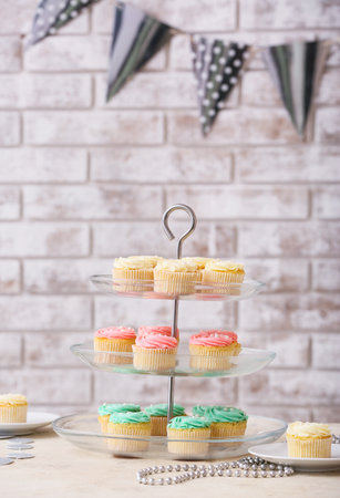 Dessert stand with tasty cupcakes and beads near brick wallの写真素材