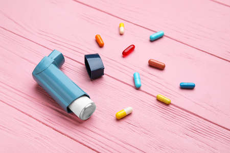 Modern inhaler and pills on color wooden backgroundの写真素材