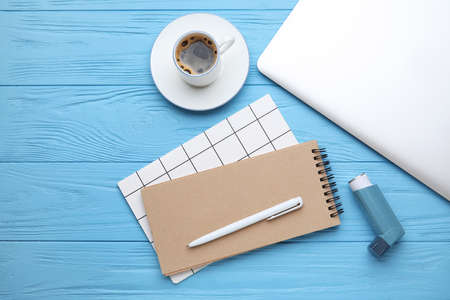 Composition with inhaler and notebooks on color wooden background