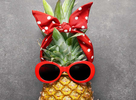 Fresh pineapple with stylish female accessories on dark backgroundの写真素材