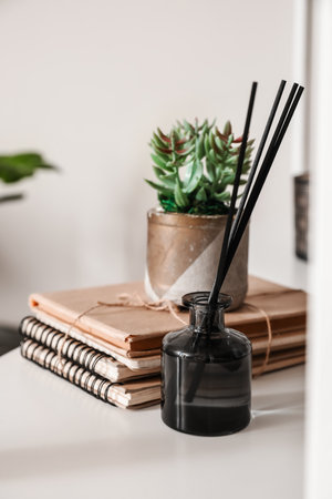Reed diffuser with houseplant and notebooks on table in roomの写真素材