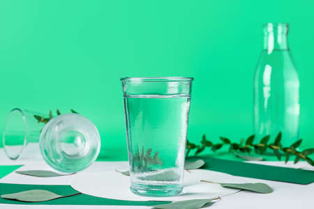 Creative composition with glasses of water on color background