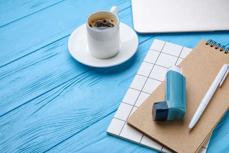 Composition with inhaler and notebooks on color wooden background