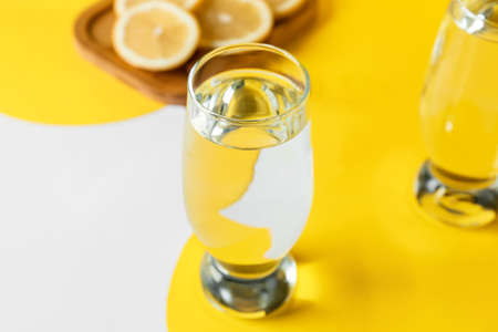 Glasses of water and lemons on color background