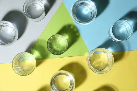 Glasses of water on color background