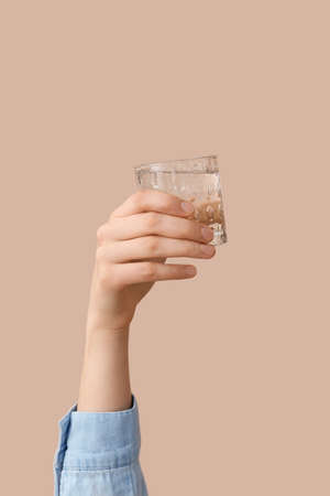 Female hand with glass of water on color backgroundの写真素材