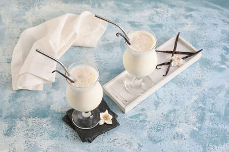 Glasses with tasty vanilla milkshake on color background