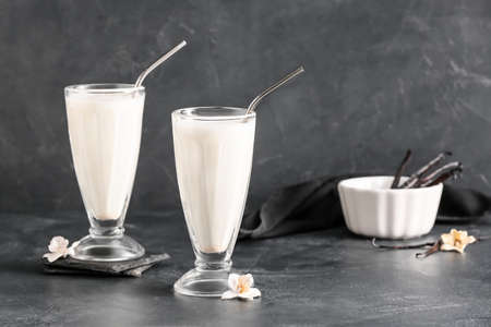 Glasses with tasty vanilla milkshake on dark backgroundの写真素材