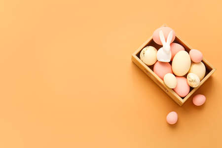 Box with beautiful Easter eggs on color background