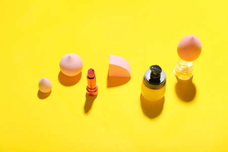 Different decorative cosmetics and makeup sponges on color background