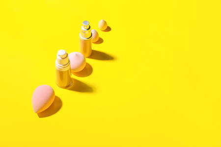 Bottles of makeup foundation and makeup sponges on color backgroundの写真素材
