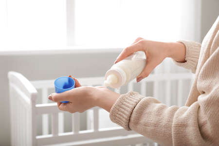 Woman checking temperature of baby formula, closeup