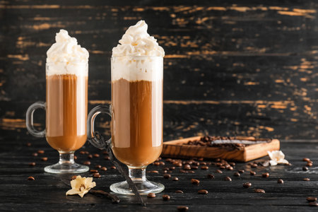 Glass cups of tasty coffee with vanilla on dark wooden background