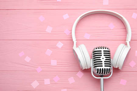 Microphone with headphones and confetti on color wooden backgroundの写真素材