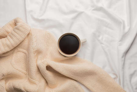 Cup of coffee and sweater on bedの写真素材