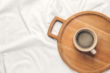 Wooden tray with cup of coffee on bedの写真素材