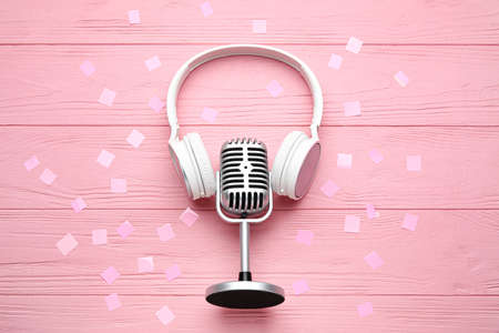 Microphone with headphones and confetti on color wooden backgroundの写真素材