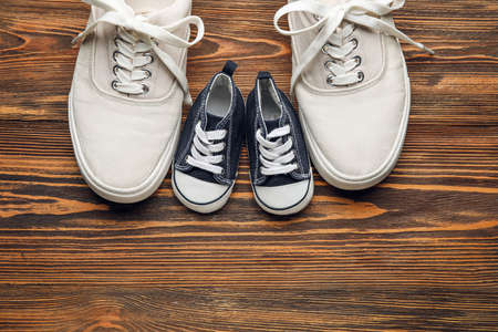 Shoes of father and son on wooden backgroundの写真素材