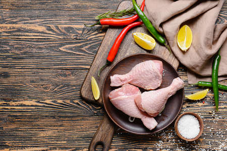 Plate with raw chicken legs on wooden backgroundの写真素材