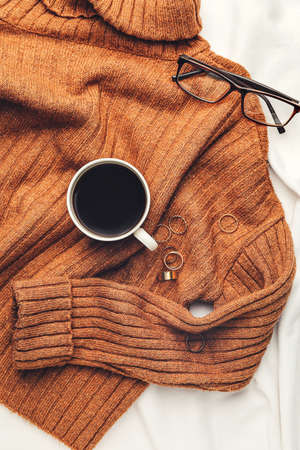Cup of coffee and sweater on bedの写真素材