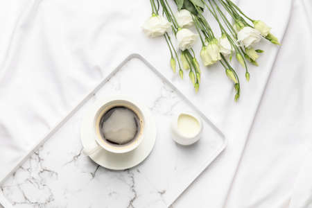 Tray with cup of coffee and flowers on bedの写真素材