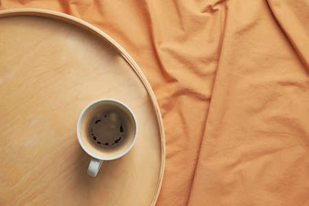 Tray with cup of coffee on bed