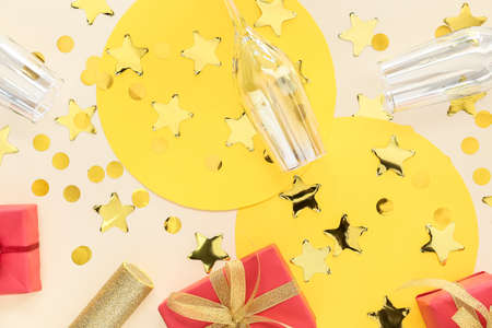Glasses with gift boxes and confetti on color background