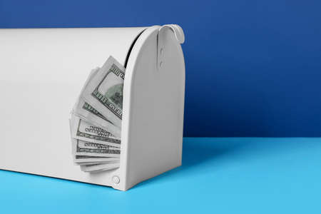 Mail box with money on color background