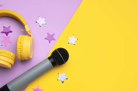 Modern microphone with headphones and confetti on color backgroundの写真素材